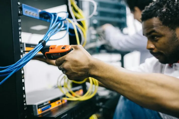 Technician connecting network cables in a server rack
